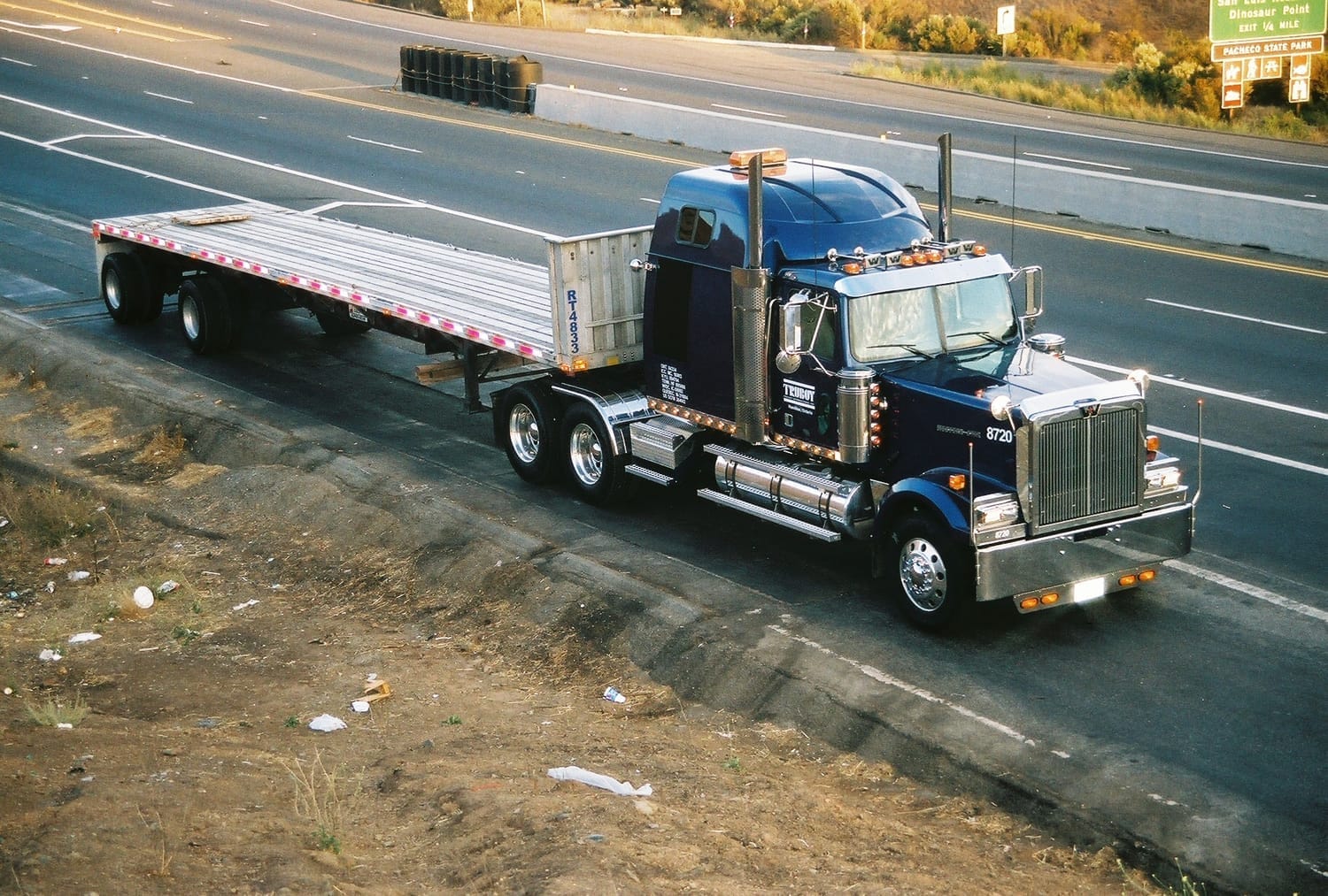 Western Star tractor with empty flatbed trailer staged along the highway